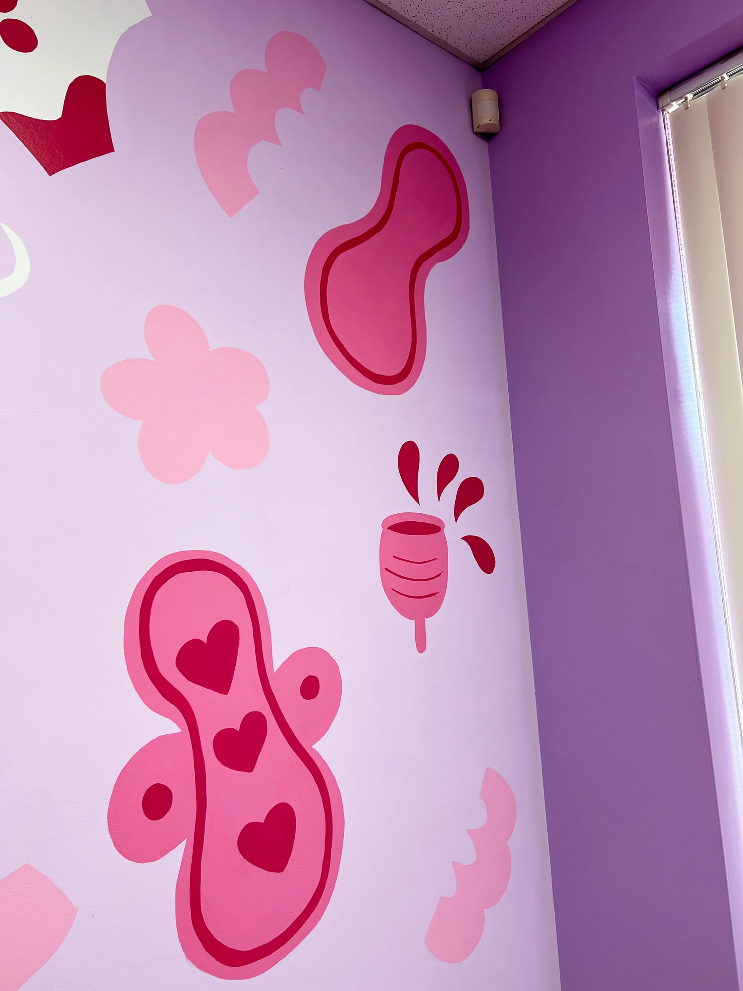The mural wrapping around a corner of the room in pink and purple