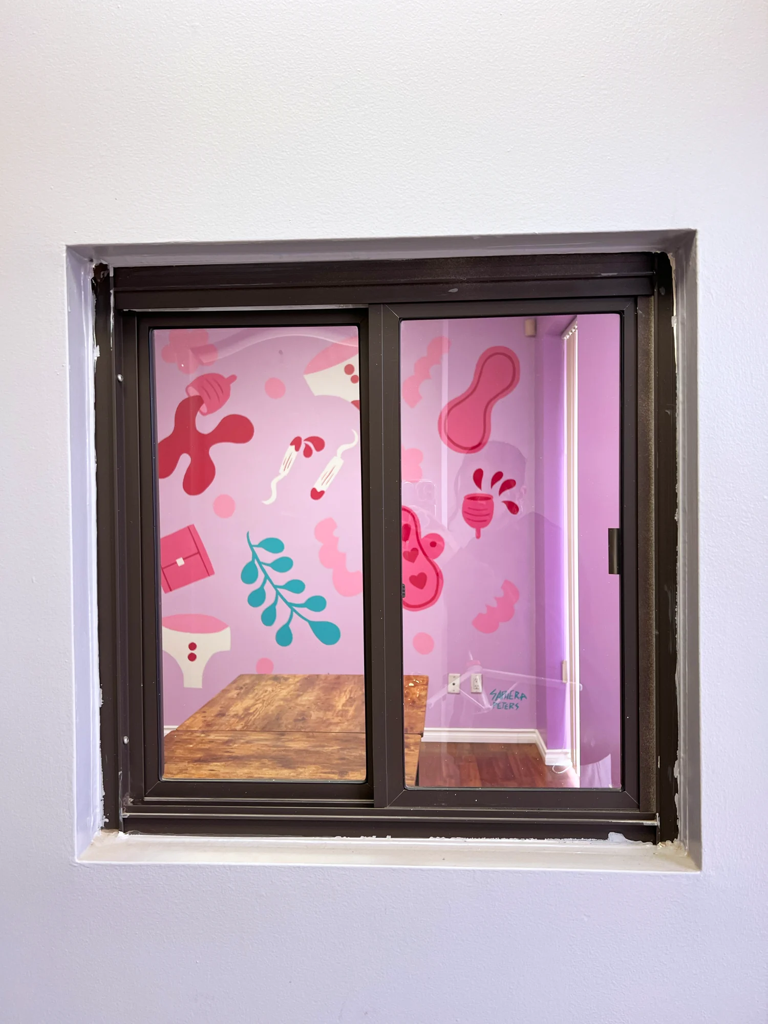 The mural seen through an interior window of the community space