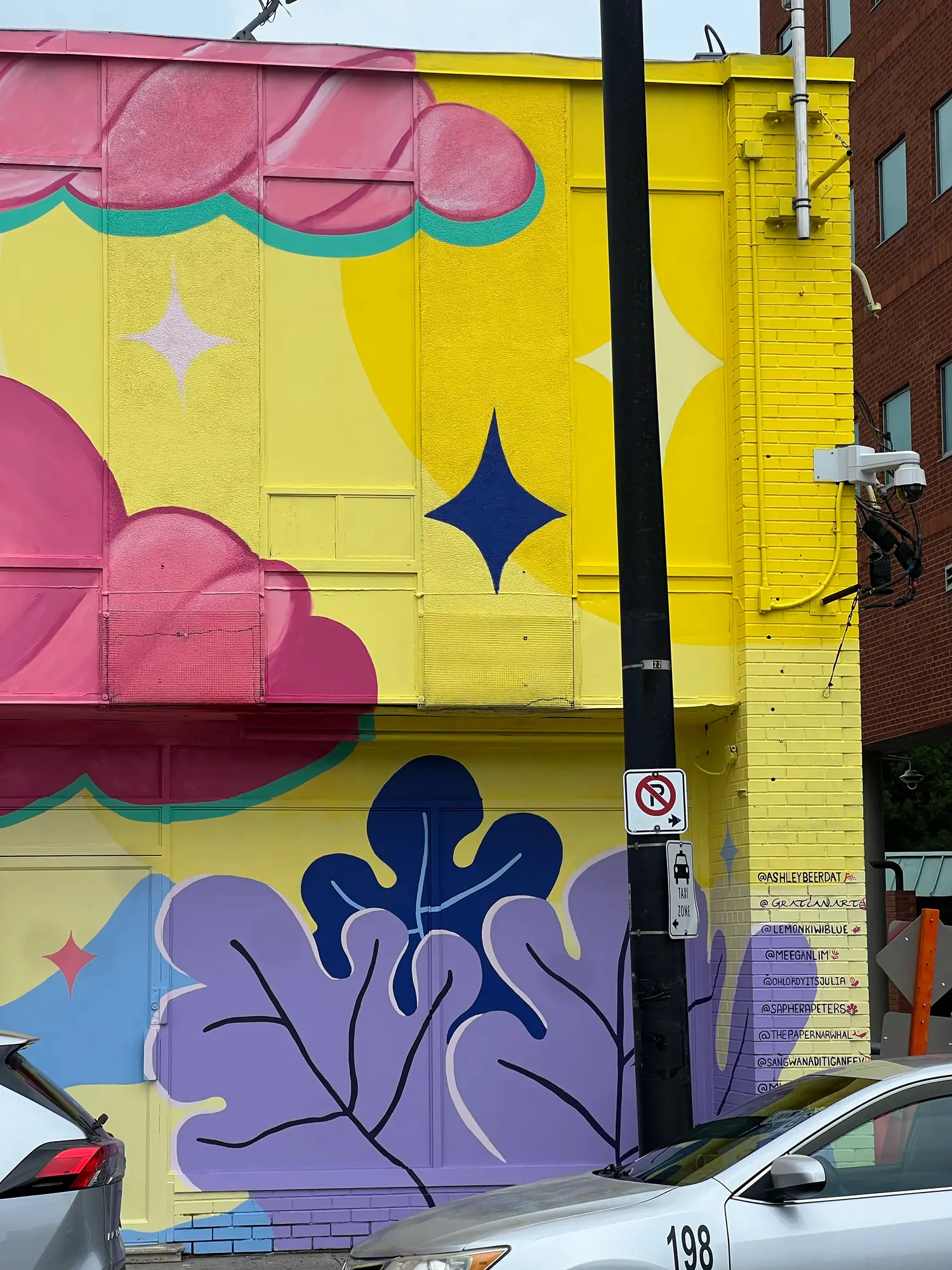 Corner of the mural in yellow and purple with a large pink cloud and a four-point star