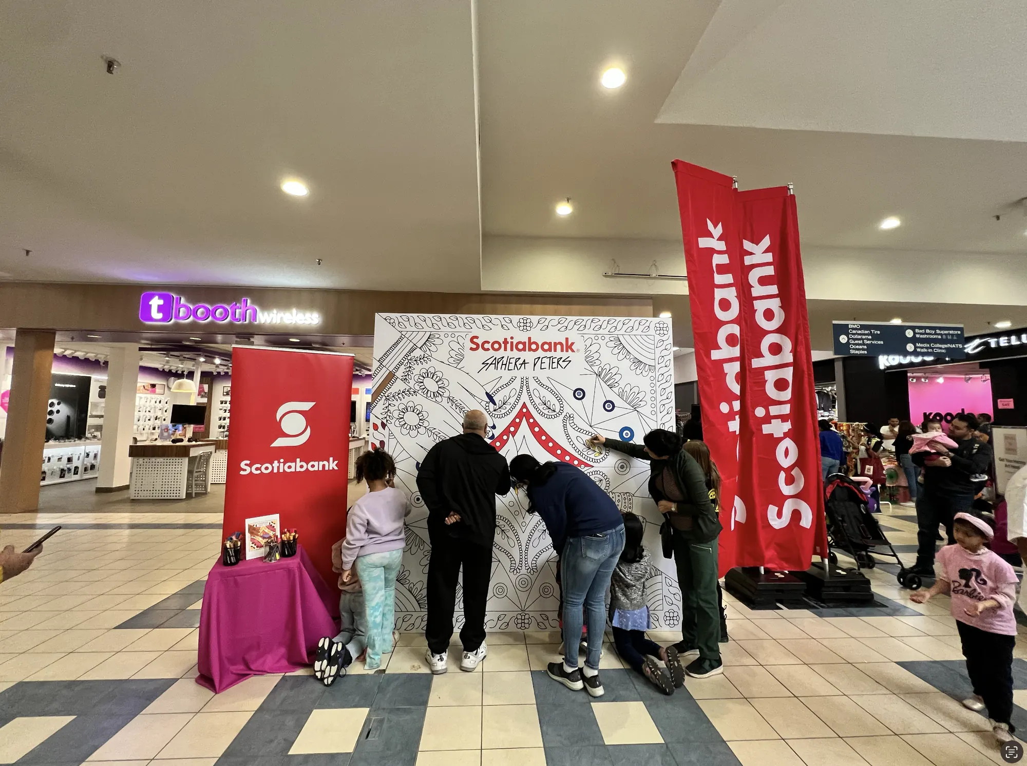 A crowd gathered around the colouring wall at Shoppers World Mall between Scotiabank banners