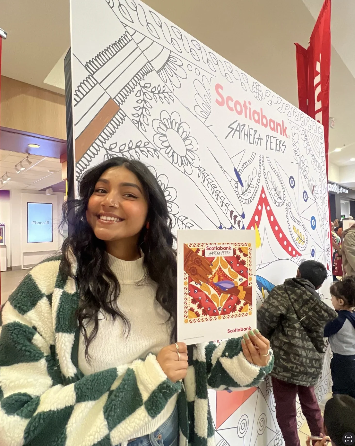 Saphera holding the coloured reference print in front of the colouring wall
