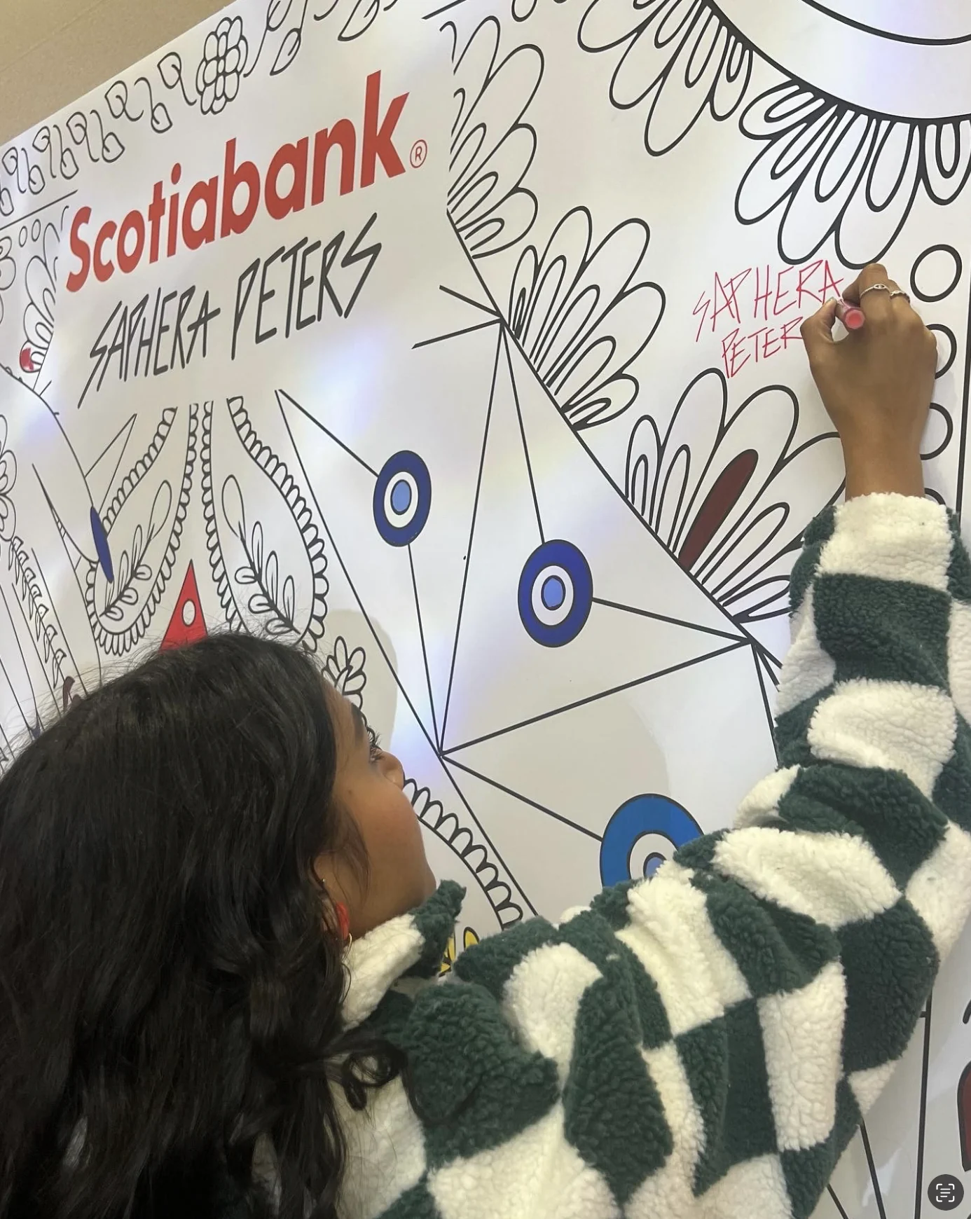 Close view of Saphera adding detail to the wall with a marker